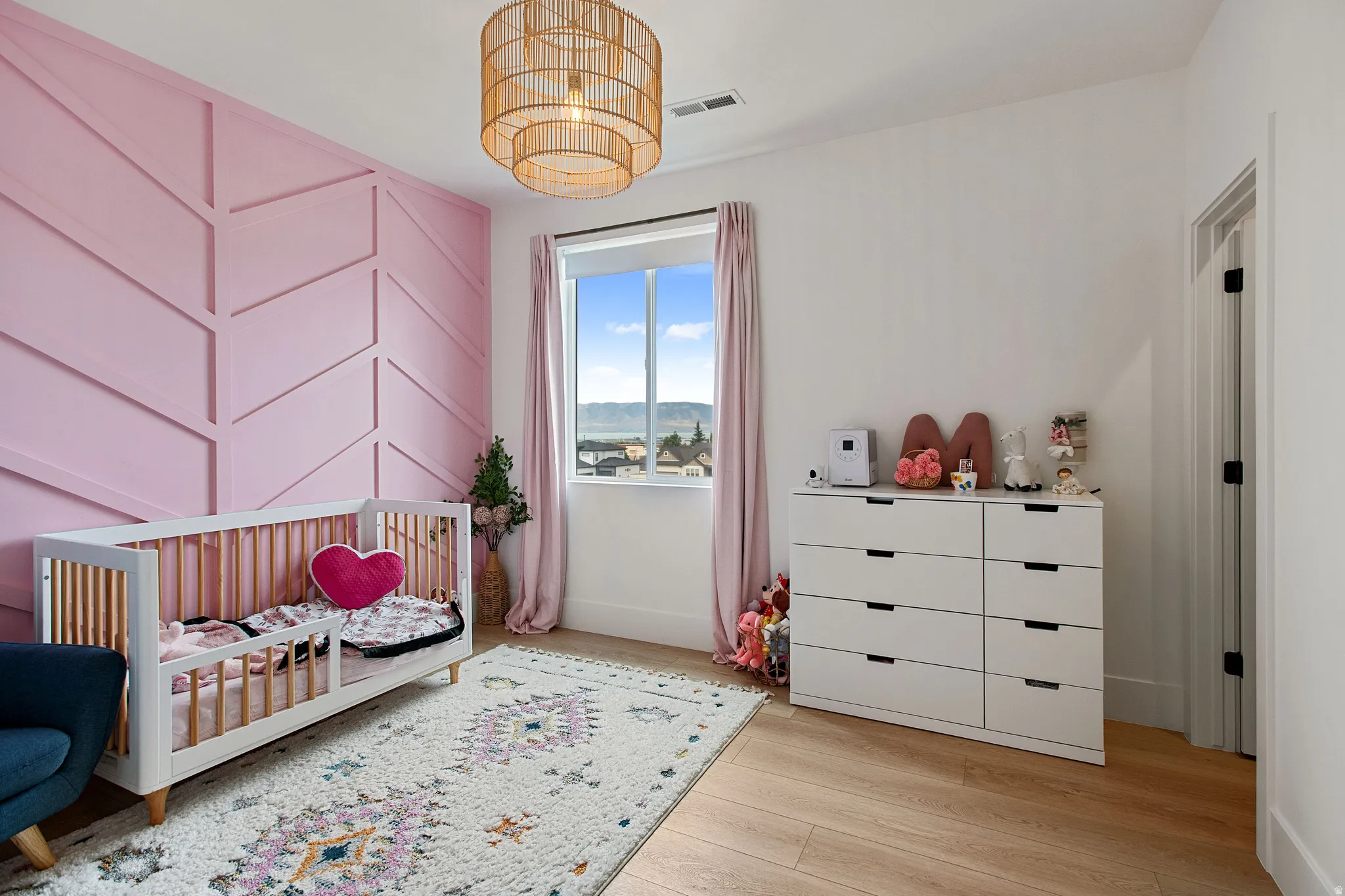 Accent wall with a chevron pattern, light wood-finish flooring, recessed lighting, and a window with mountain scenery