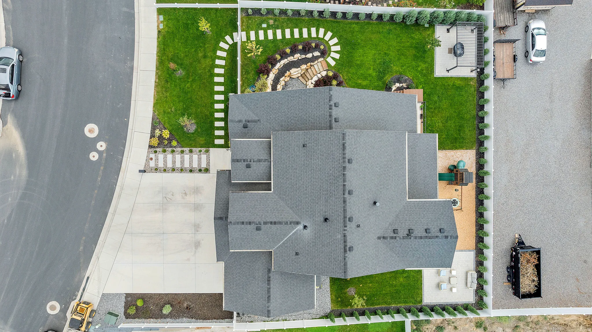 Expansive backyard featuring a manicured lawn, paver patio, and stone accent landscaping