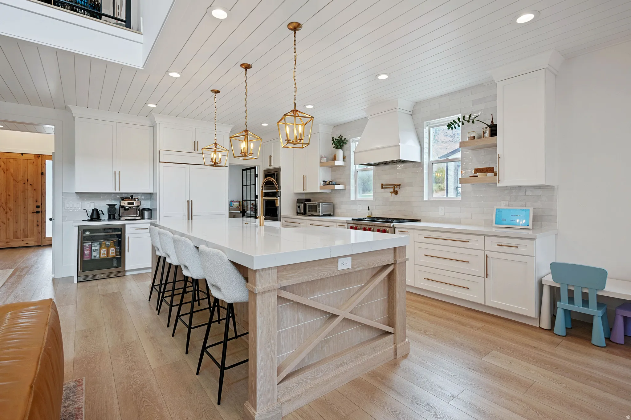 Kitchen featuring a large island with seating, white shaker cabinetry, panel-front refrigerator, and light wood-finish flooring