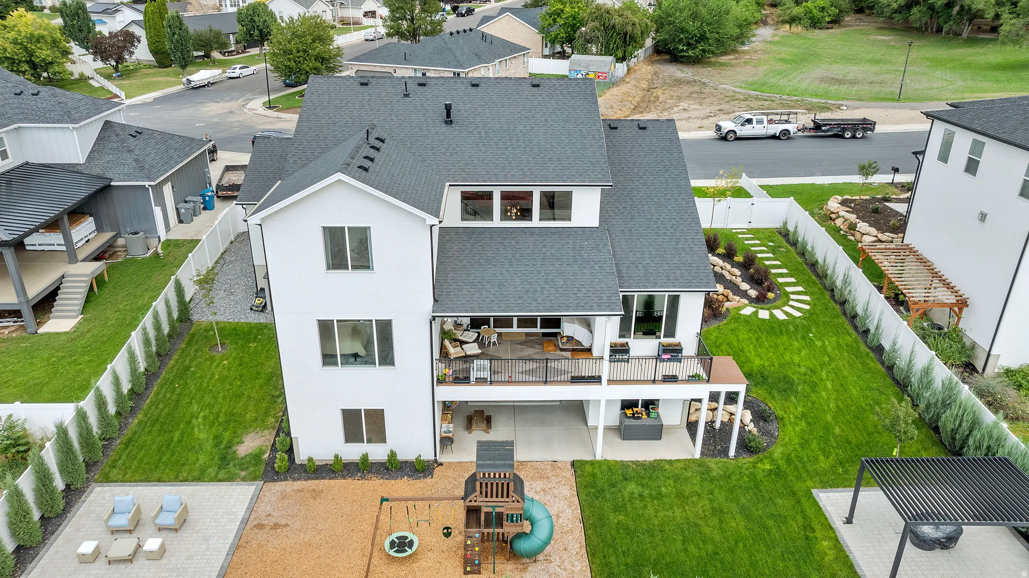 Spacious backyard featuring a manicured lawn, stone paver patio, multi-level deck, and established perimeter landscaping