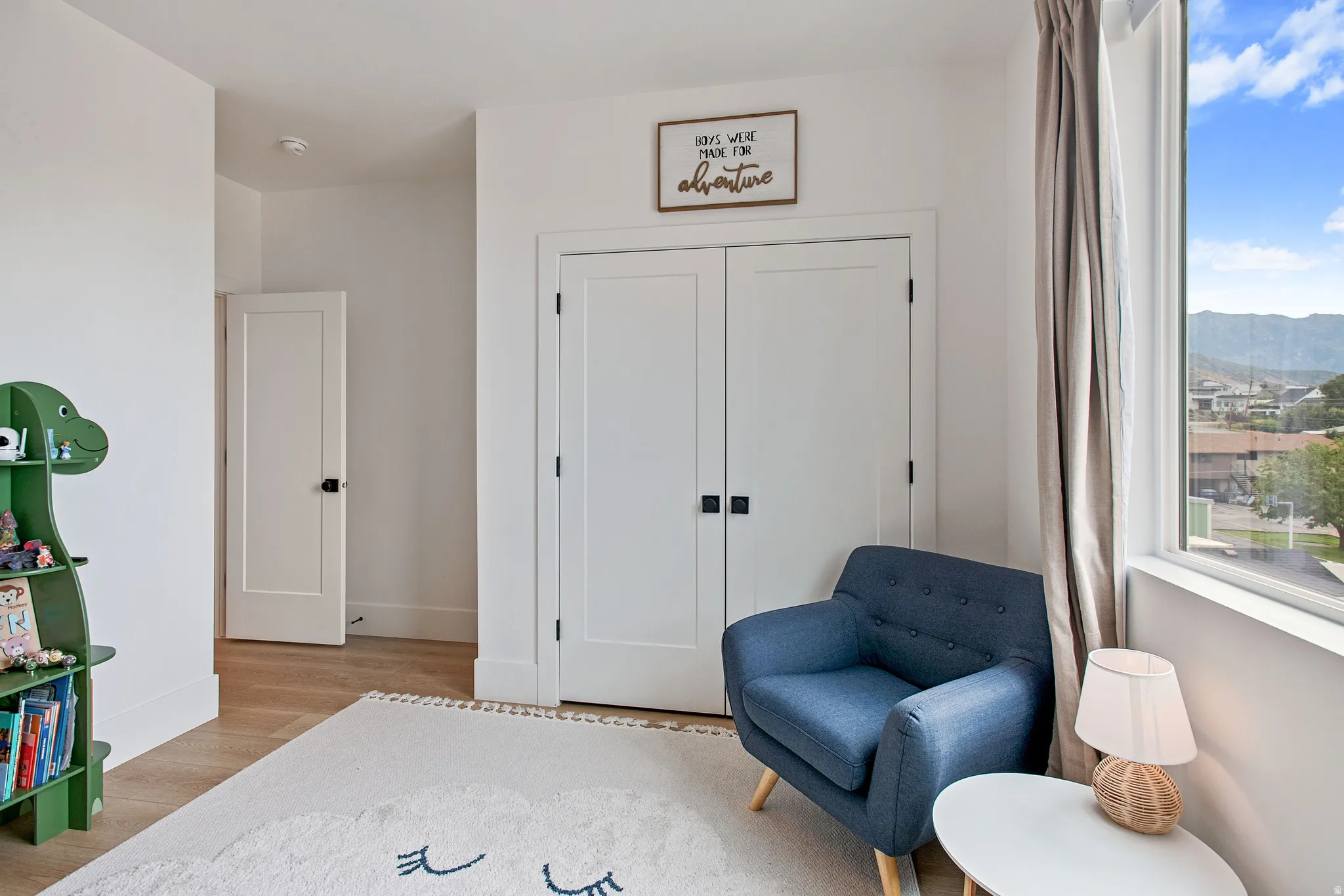 Light-filled room with wood-finish flooring, white walls, and a large window