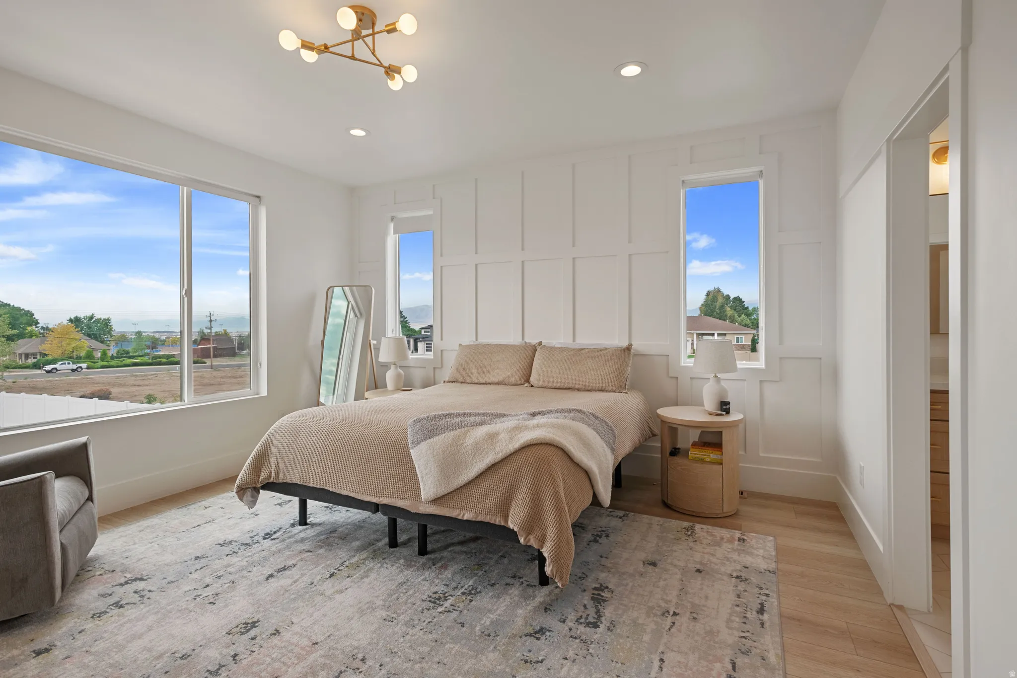 Board and batten accent wall, wood-finish flooring, large picture window, modern chandelier, recessed lighting