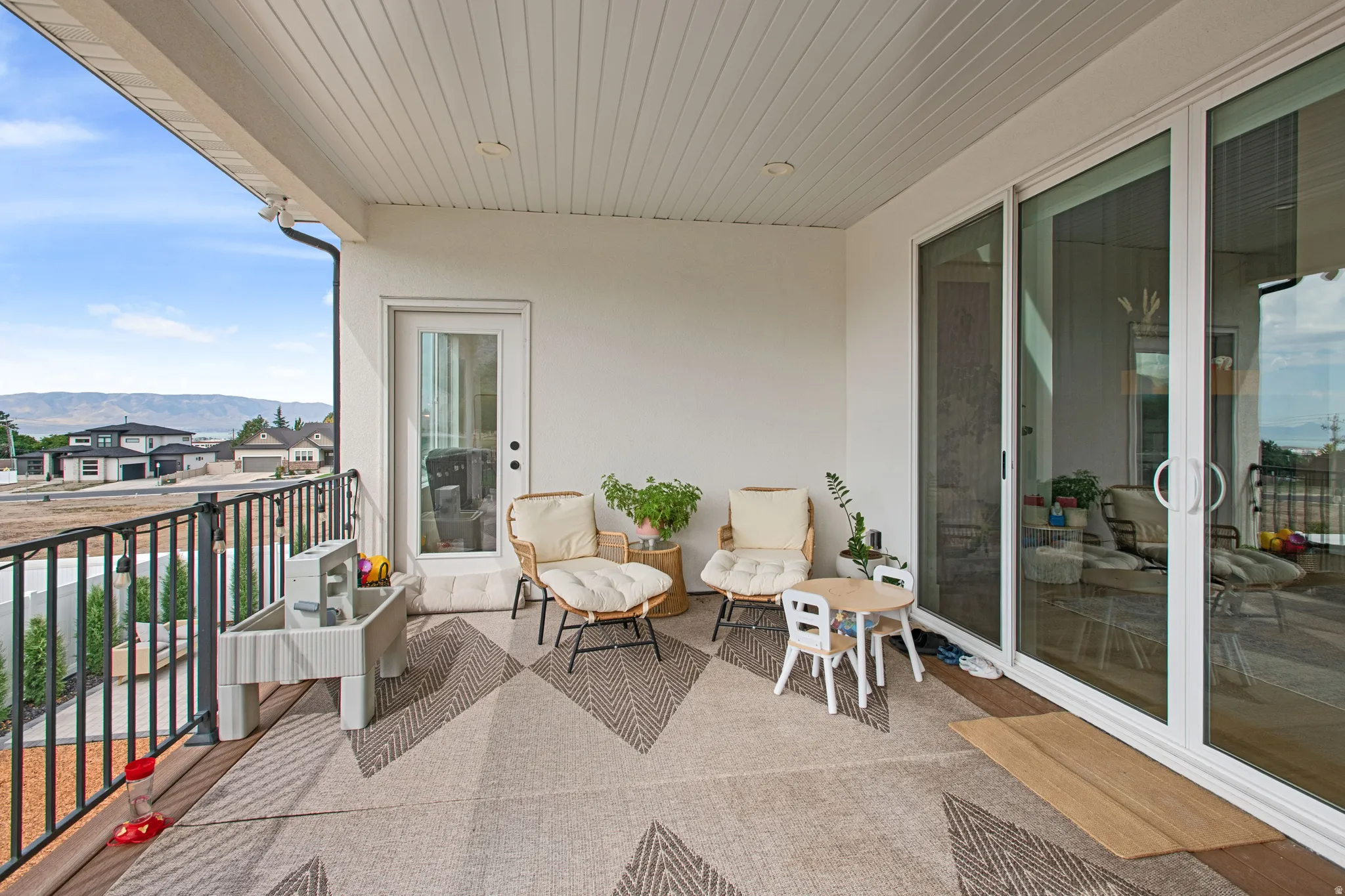 Outdoor balcony featuring a white railing, a glass-paneled door, and sliding glass doors