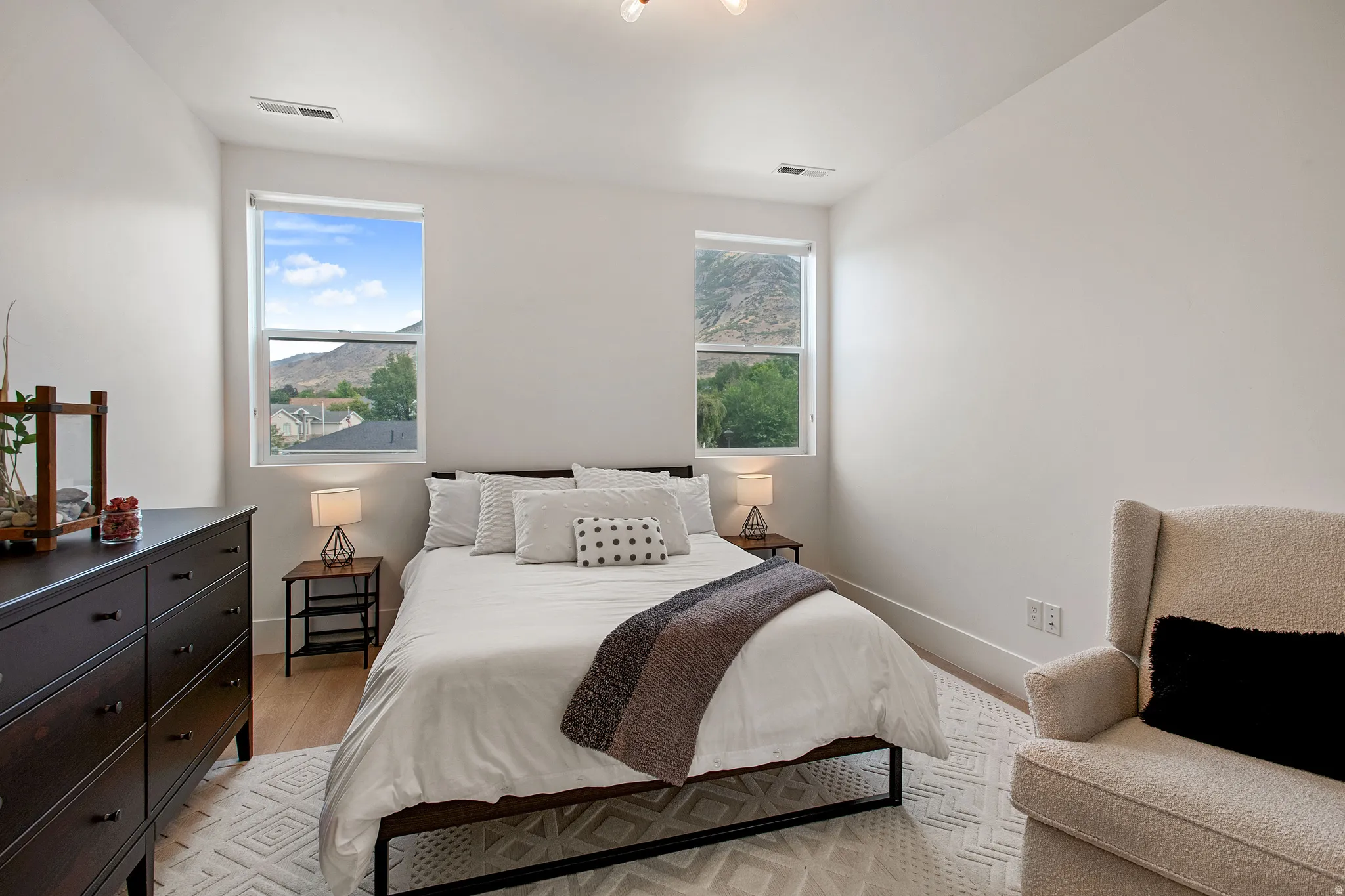 Recessed lighting, wood-finish flooring, two large windows, white walls, and prominent mountain scenery