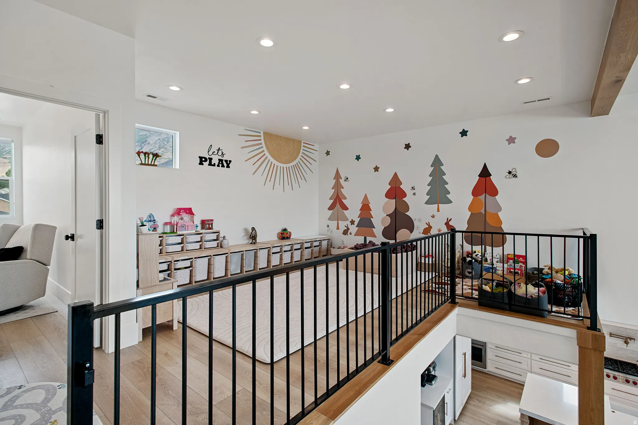 Loft area with recessed lighting, wood-finish flooring, white walls, and black metal railings