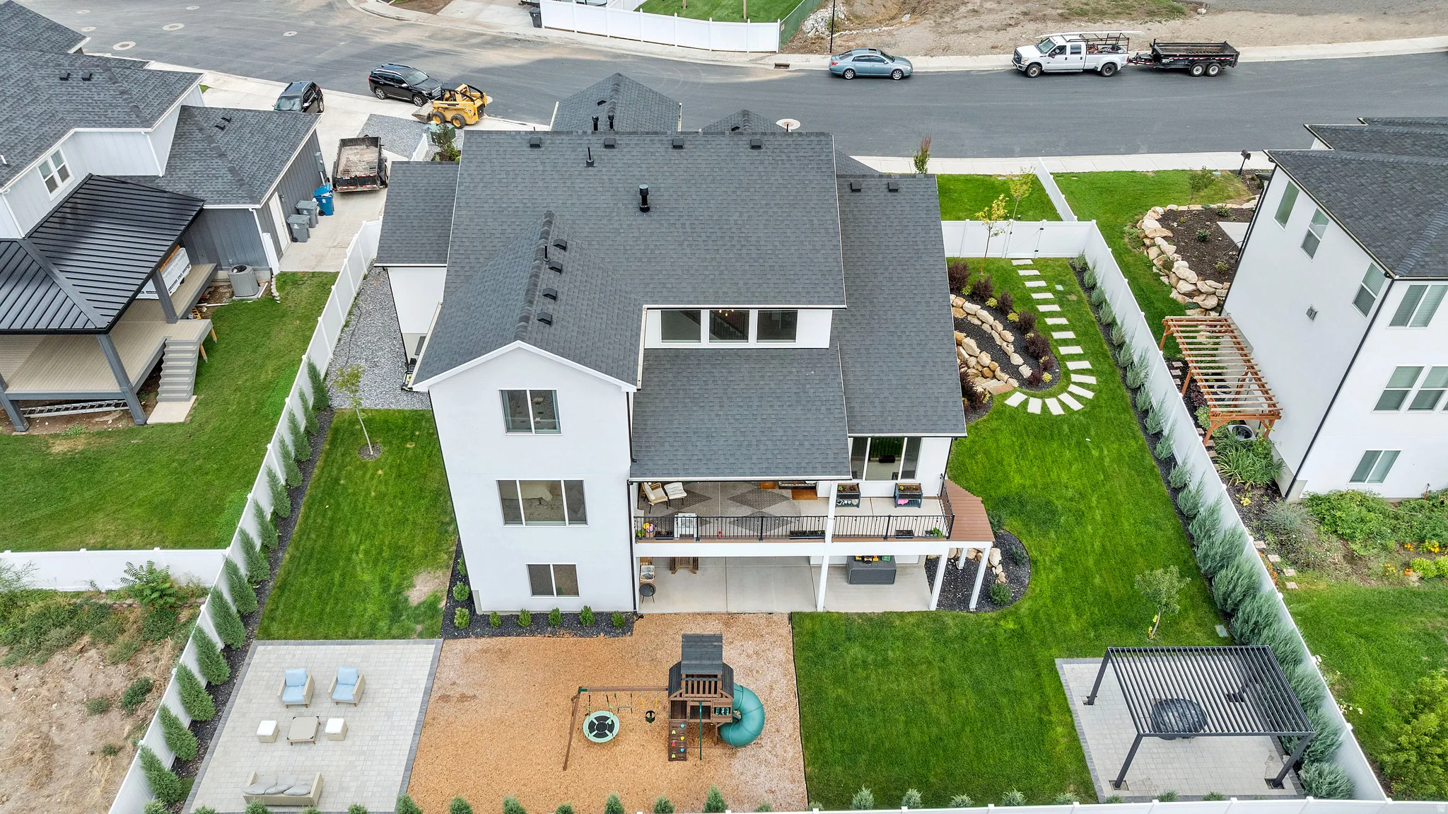Modern three-story residence with a crisp white exterior and charcoal asphalt shingle roofing