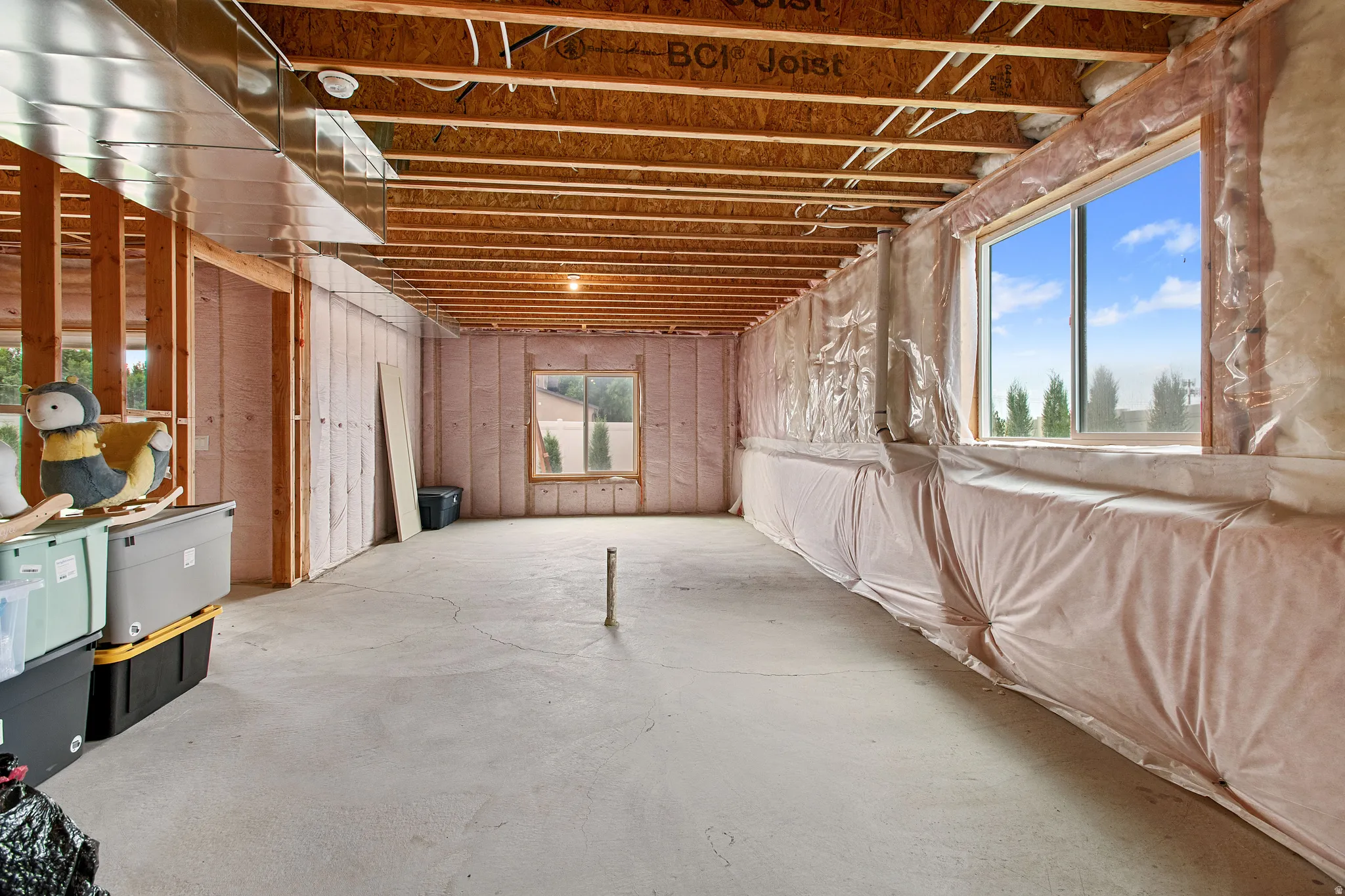 Unfinished basement featuring exposed wood joists, concrete flooring, and multiple windows