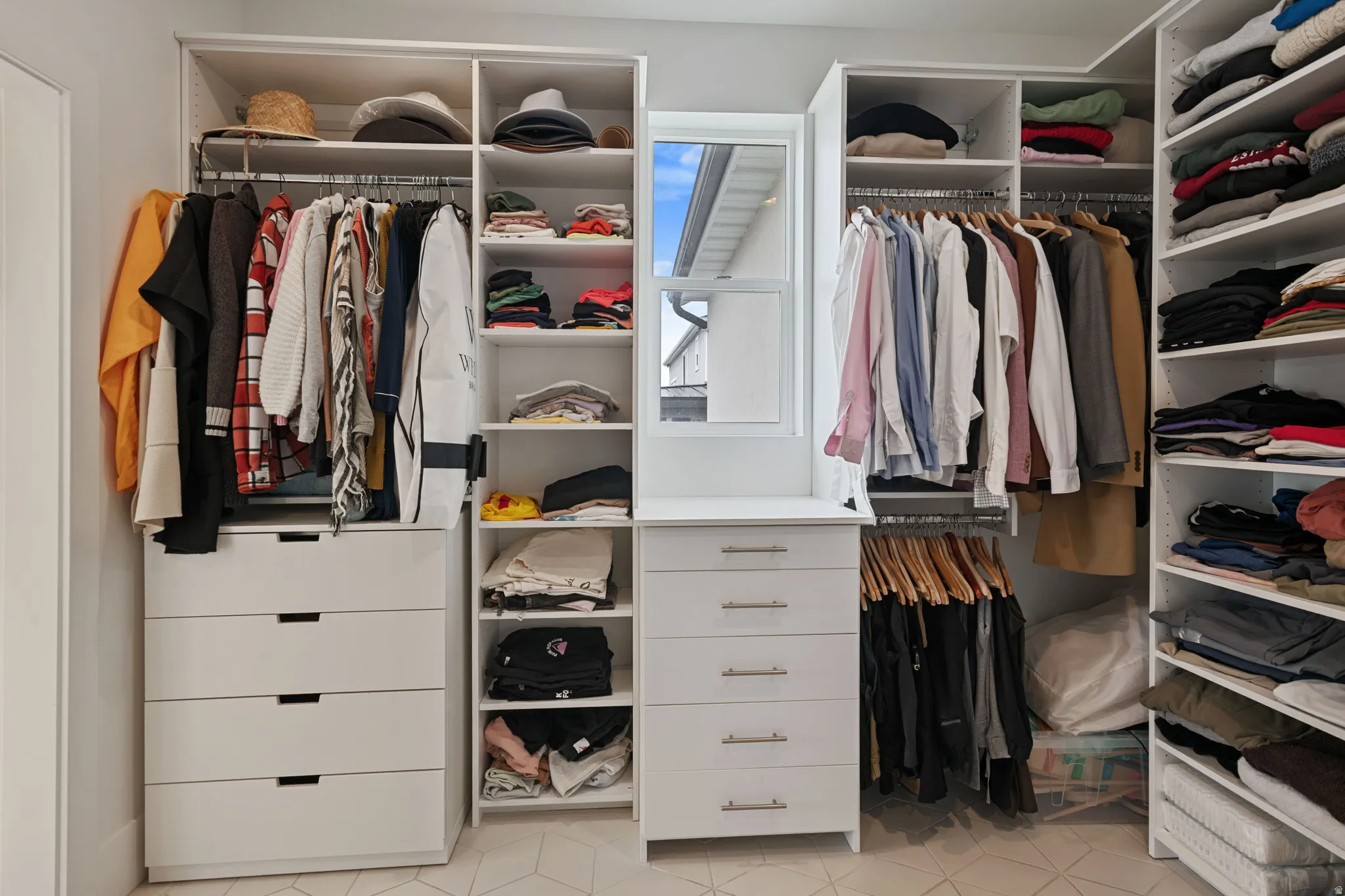 Custom closet system featuring multiple hanging rods, integrated drawer storage, and open shelving