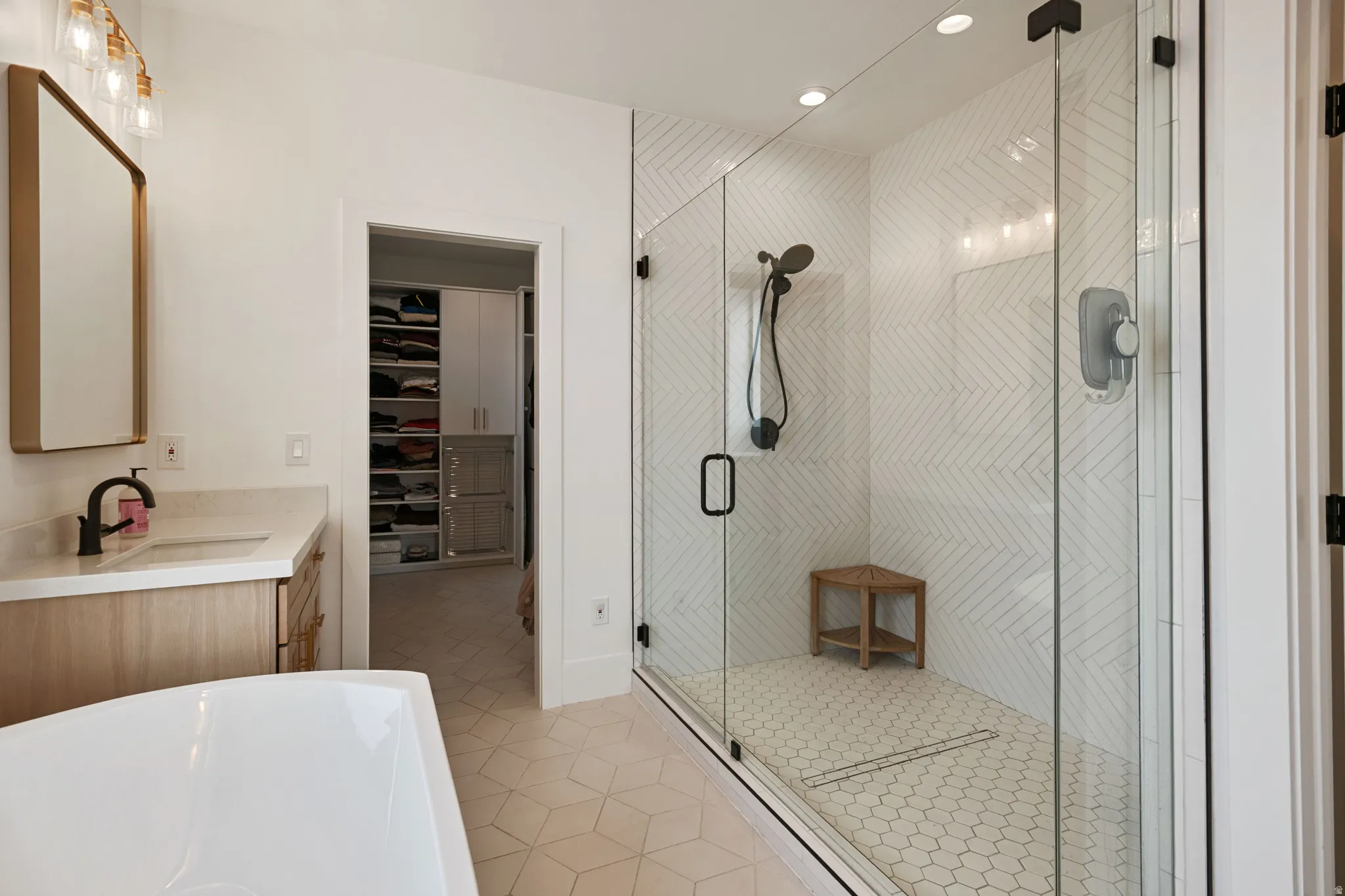 Glass-enclosed shower with chevron tile surround and hexagon tile flooring