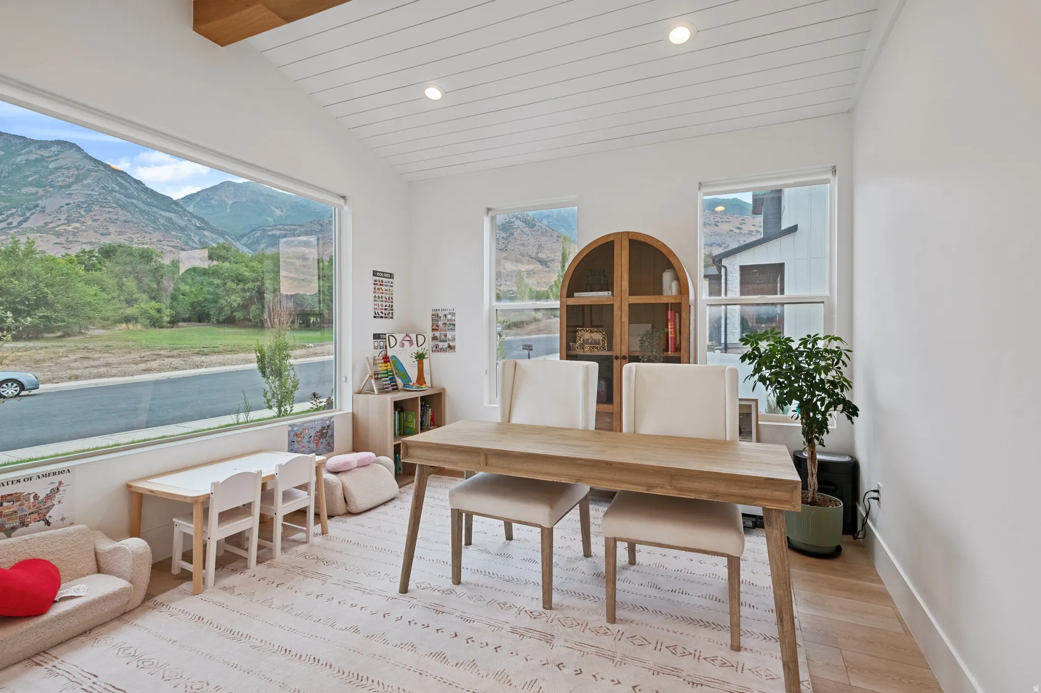 Recessed lighting, wood-finish flooring, white shiplap ceiling, expansive windows.