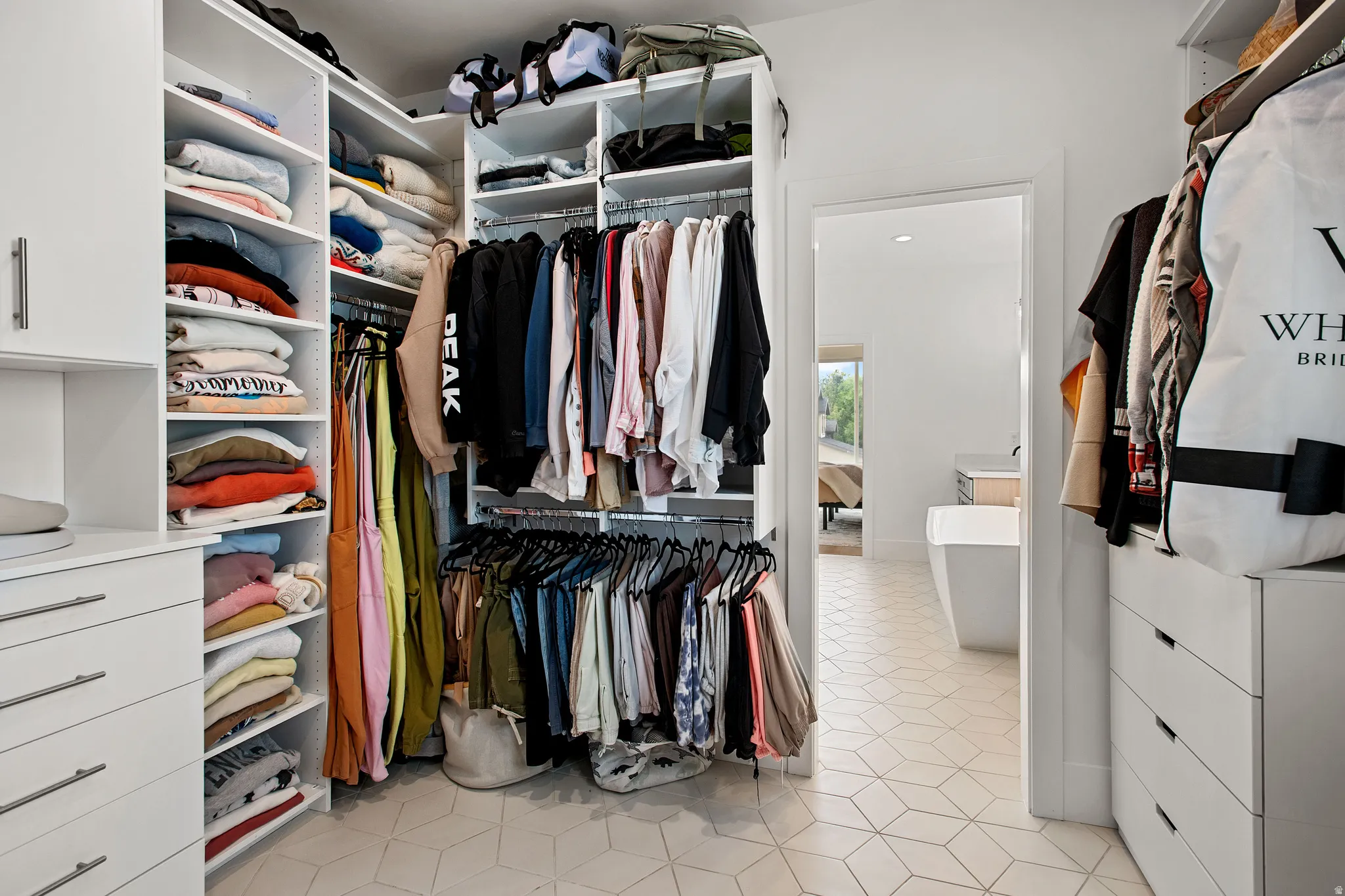 Custom closet system with white cabinetry, integrated shelving, hanging rods, and drawer storage