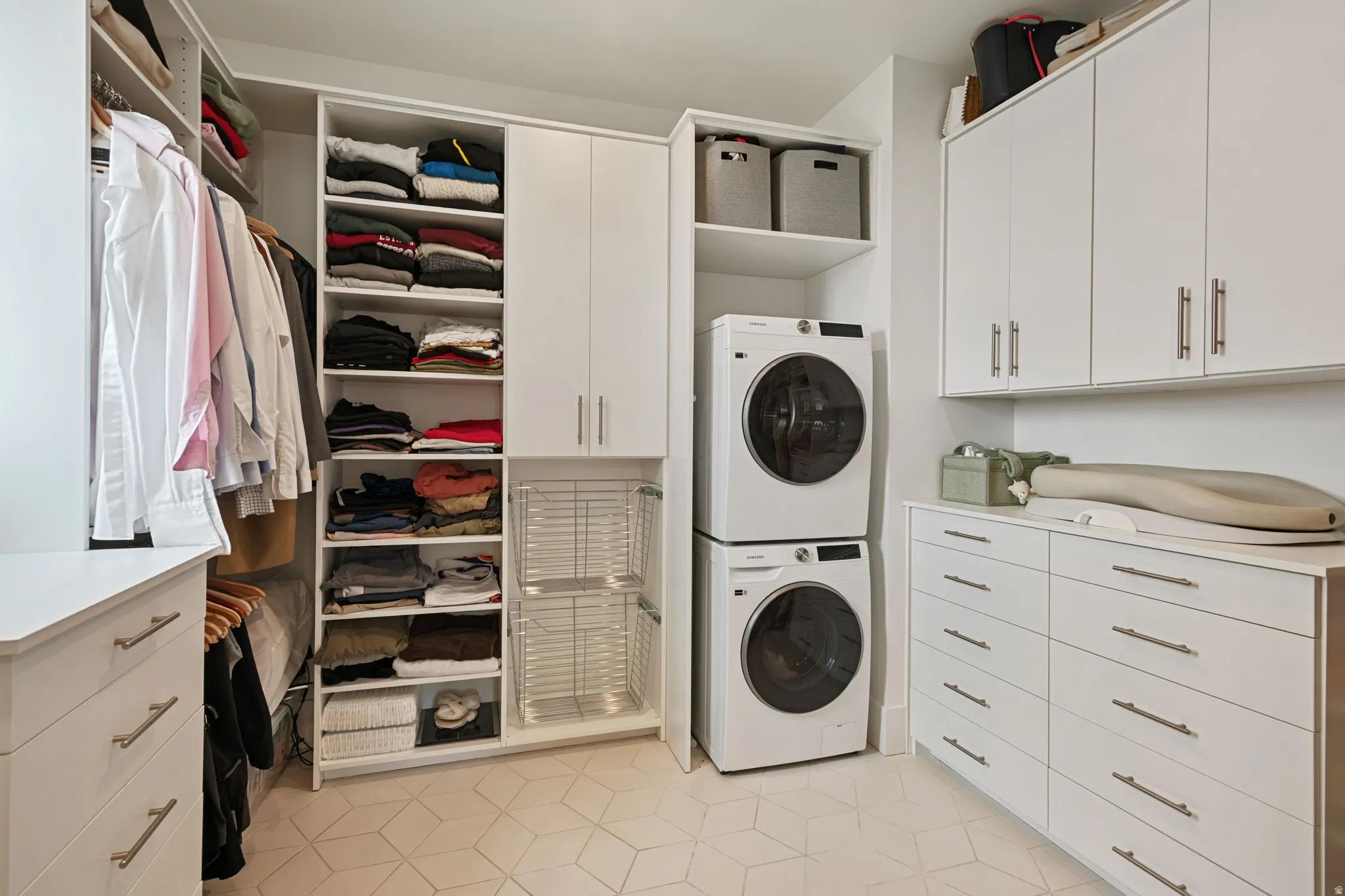 Integrated laundry appliances, extensive built-in cabinetry, custom shelving, multiple clothing rods, and hexagonal floor tile