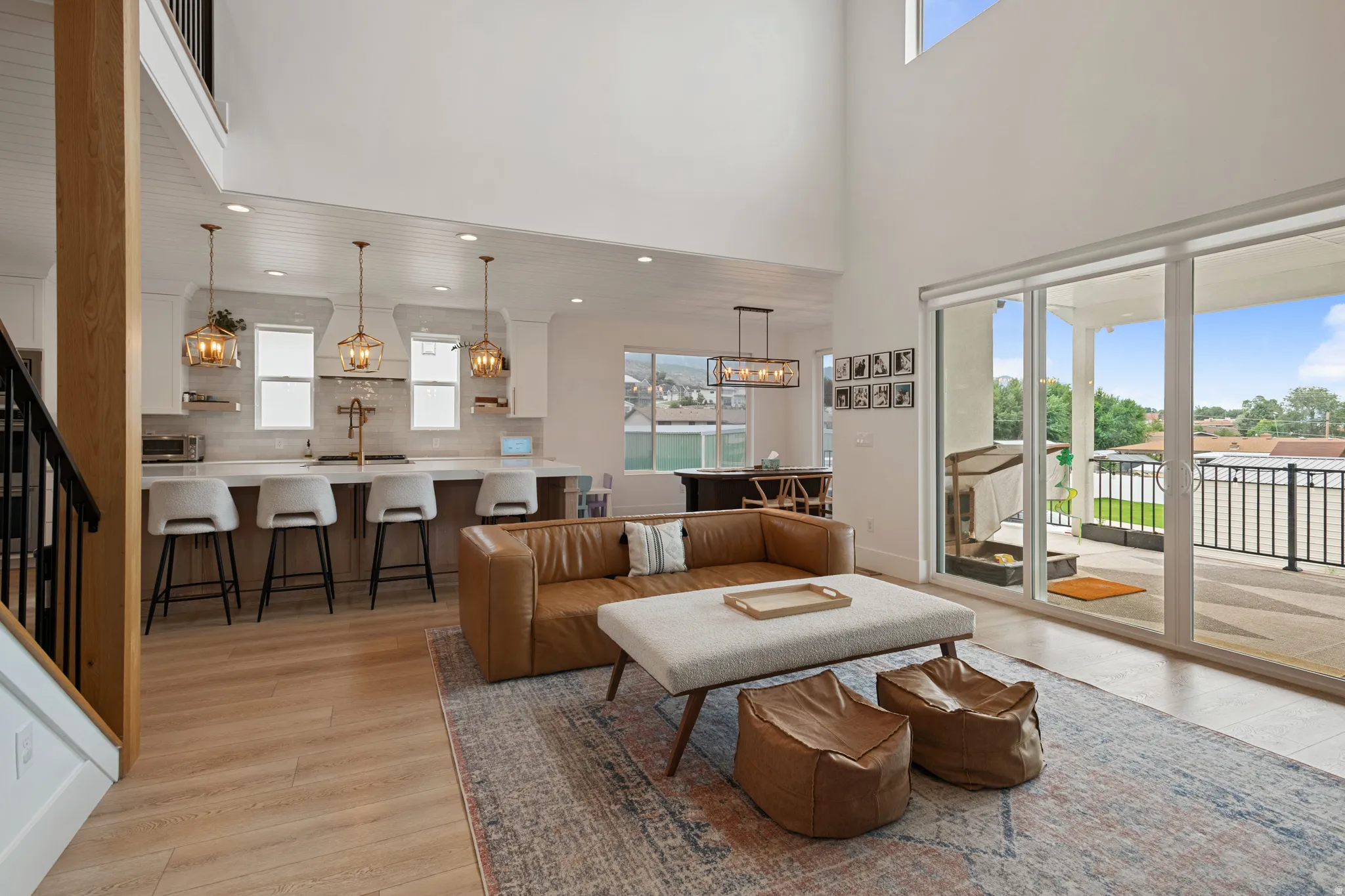Vaulted ceilings, wood-finish flooring, a kitchen island with seating, a tile backsplash, and sliding glass doors to the outdoor patio
