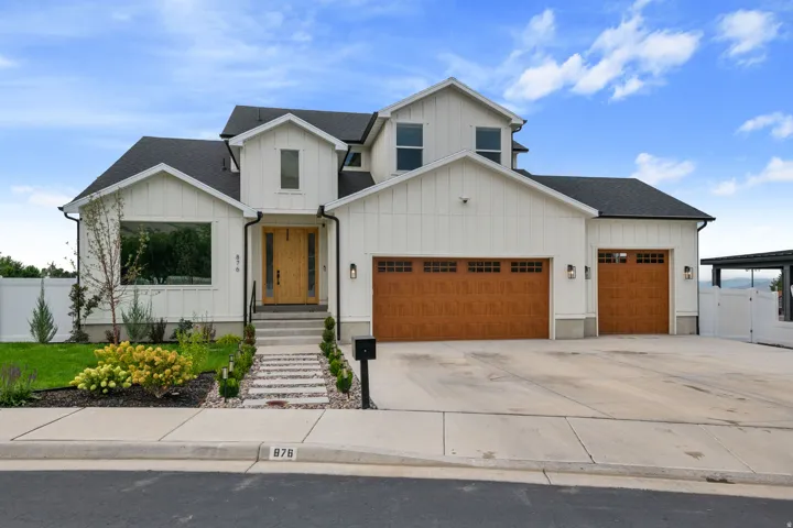 Modern farmhouse-style exterior featuring white vertical siding, a dark shingle roof, and a wood-finish front door