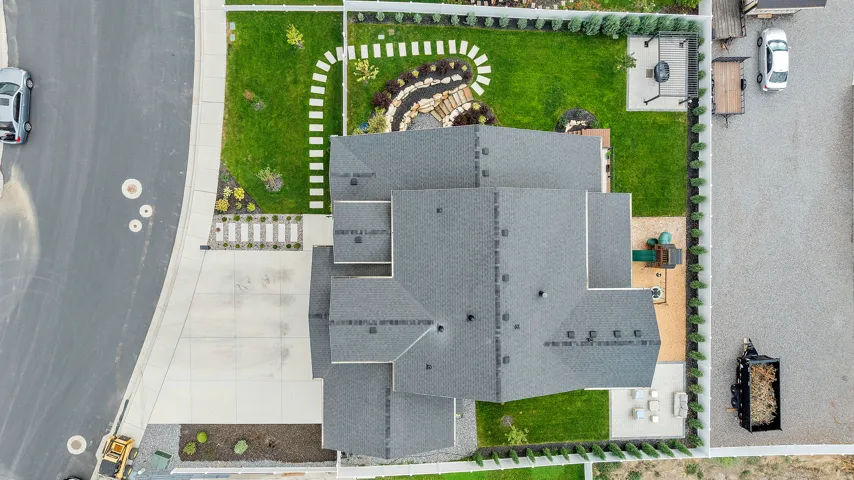 Expansive backyard featuring a manicured lawn, paver patio, and stone accent landscaping