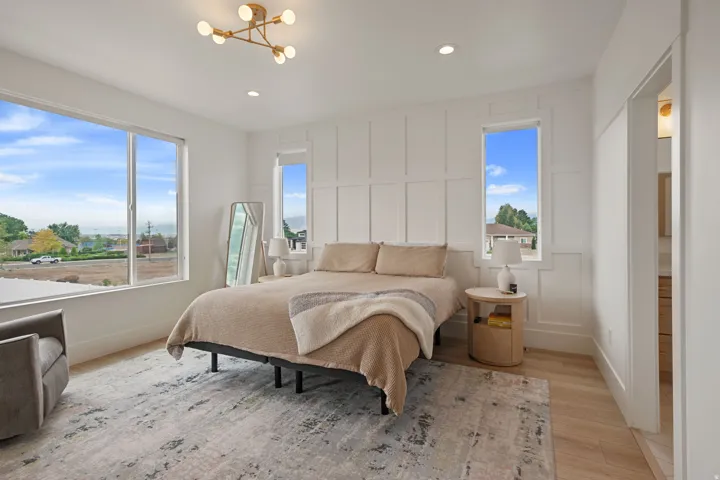 Board and batten accent wall, wood-finish flooring, large picture window, modern chandelier, recessed lighting