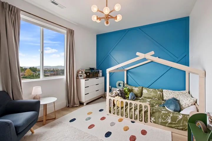 Expansive window with natural light, wood-finish flooring, accent wall with geometric paneling, and a contemporary ceiling fixture