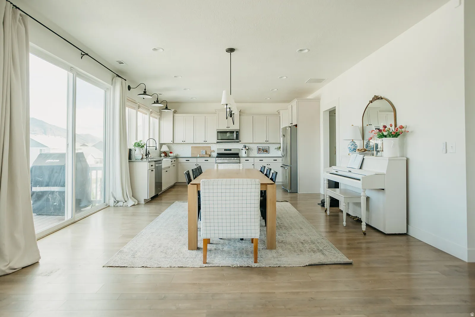 Open-concept living space with wood-finish flooring, white cabinetry, stainless steel appliances, and a sliding glass door