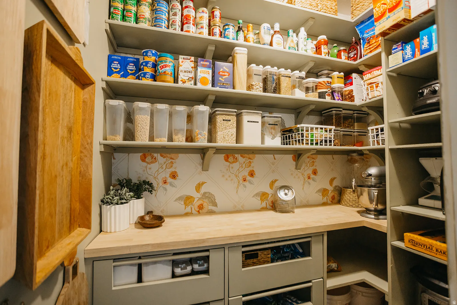 Built-in shelving, corner countertop, under-counter drawers, and decorative wallpaper