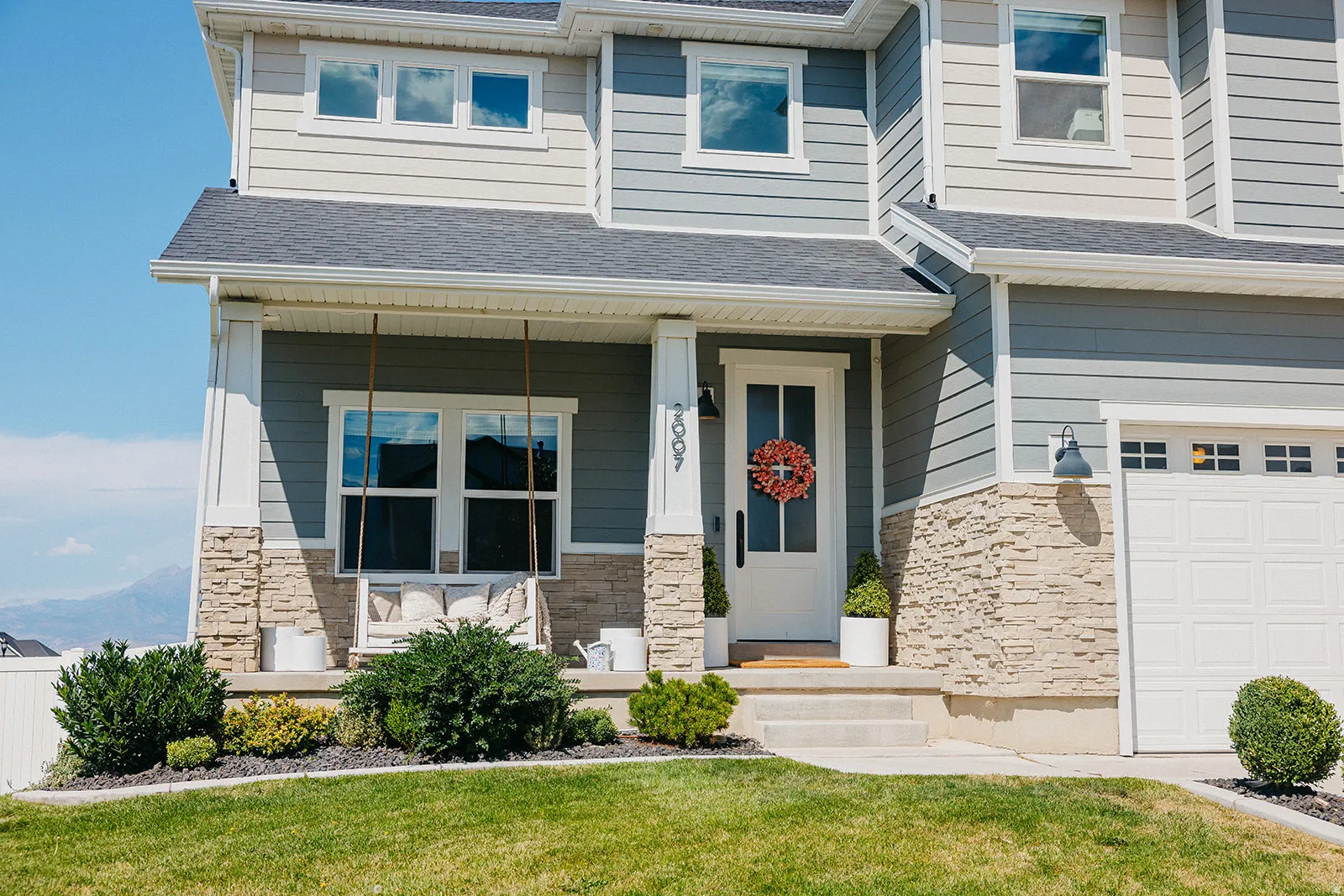 Welcoming front elevation featuring a two-story contemporary design with horizontal siding, stone veneer accents, and a covered entry portico