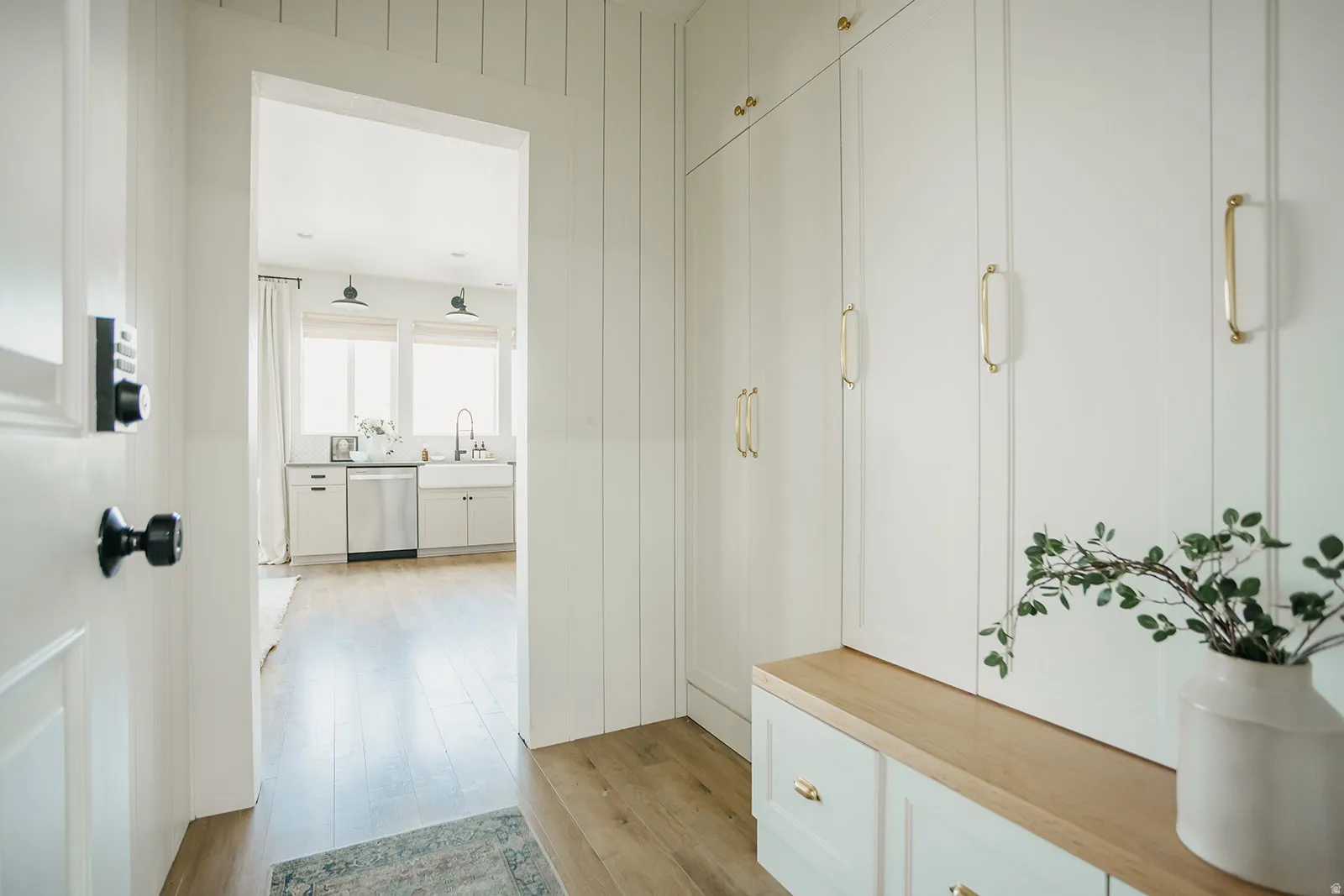 Built-in cabinetry with brass-finish hardware, wood-finish flooring, and white paneling