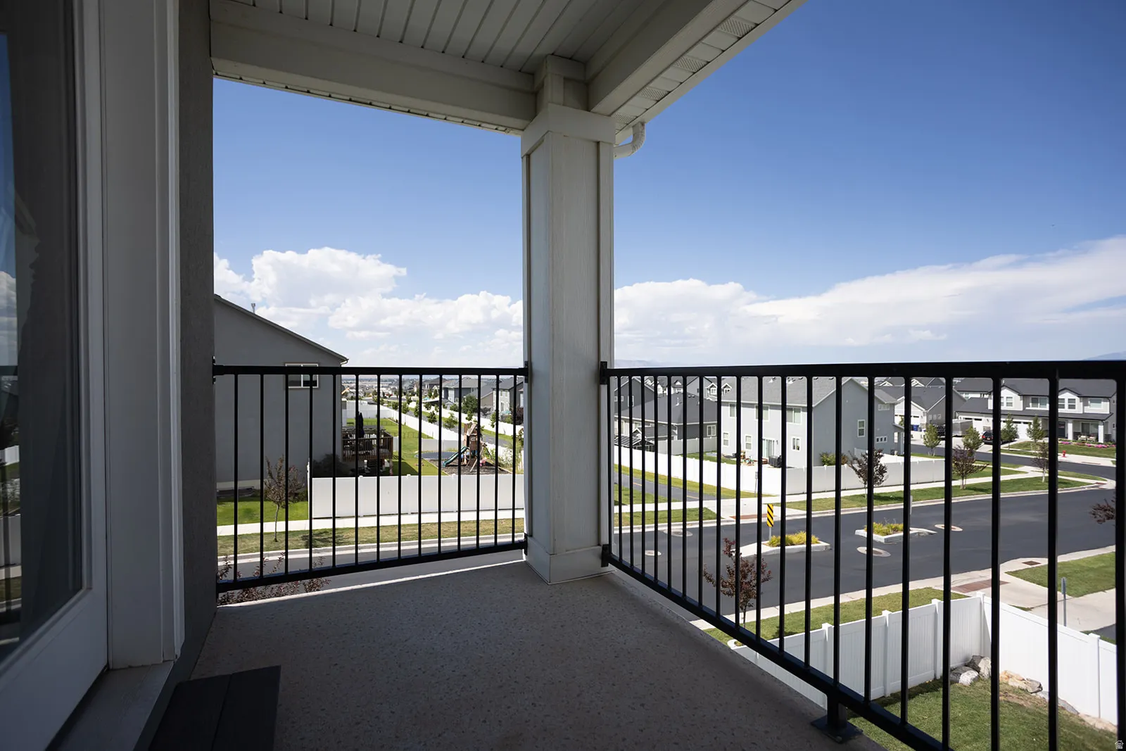 Balcony featuring a concrete surface, black metal railing, and white columns