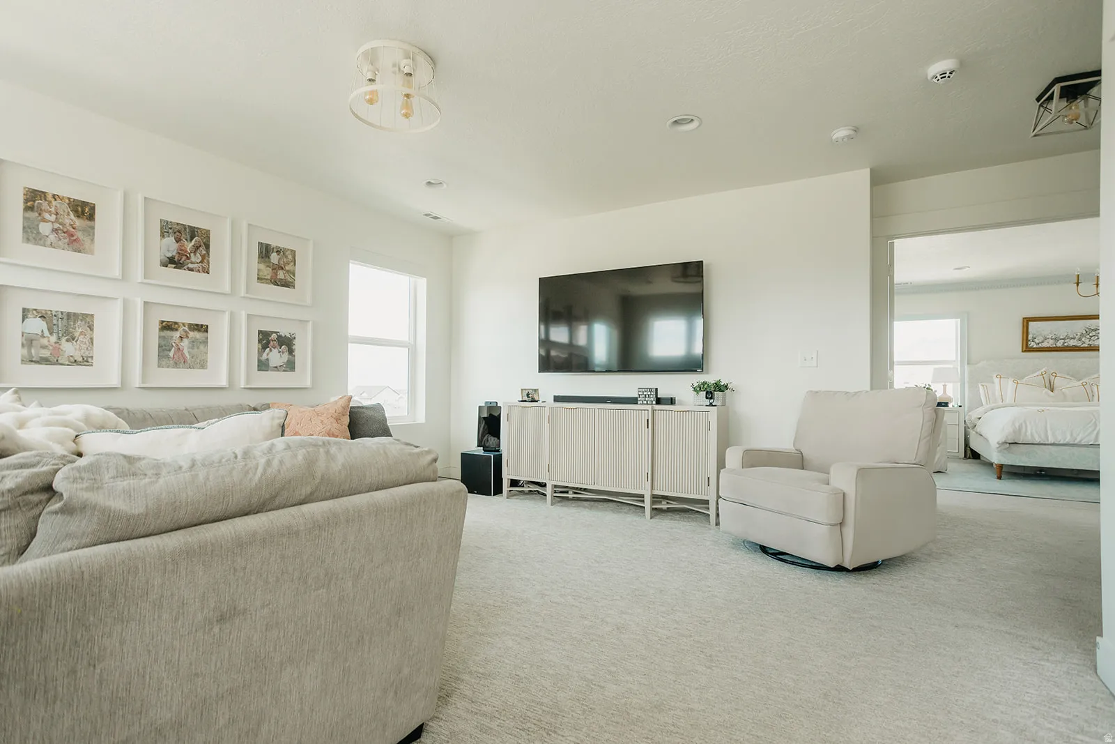 Spacious carpeted room featuring a window, ceiling-mounted light fixture, and recessed lighting