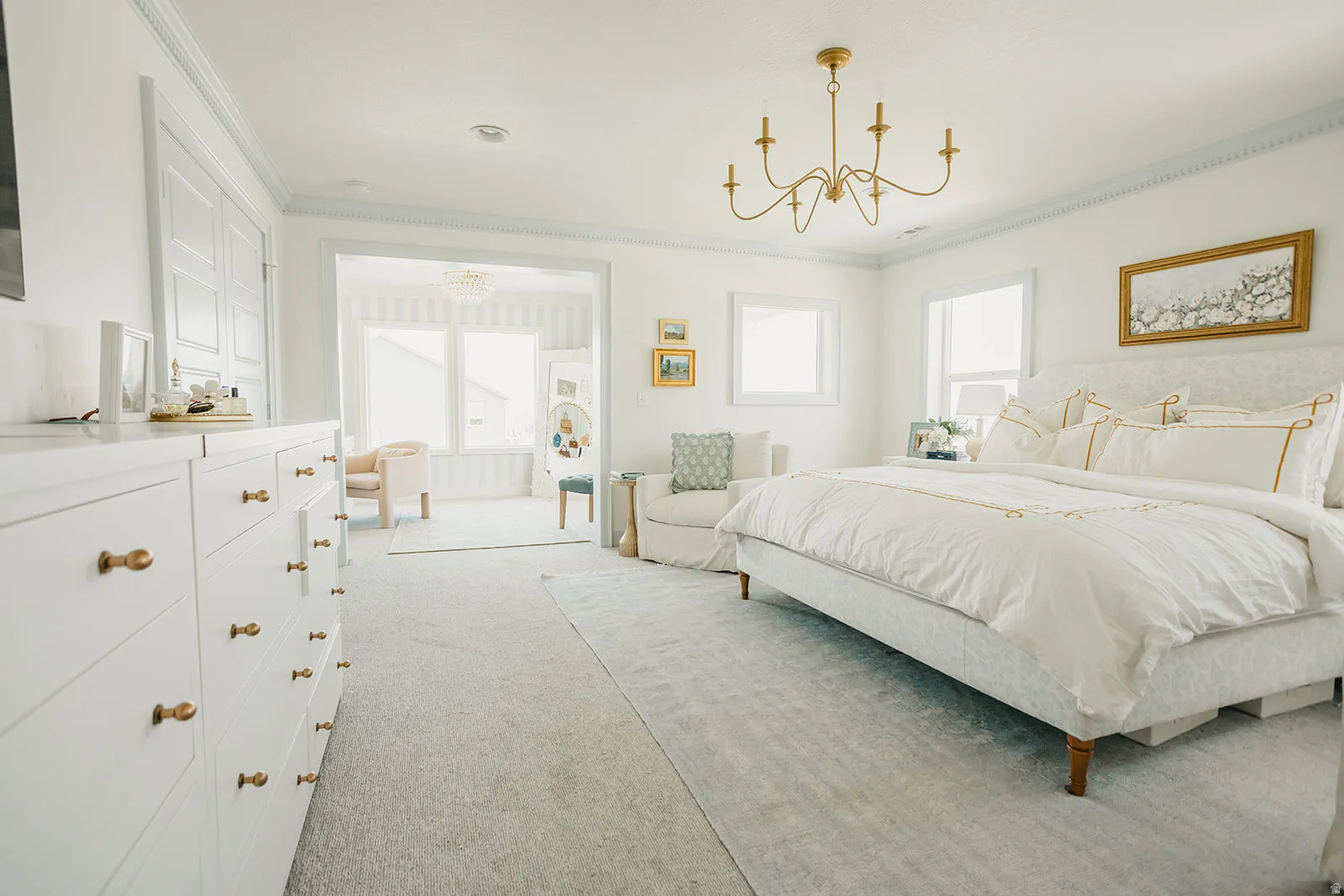 Recessed lighting, crown molding, and a brass chandelier illuminate the space