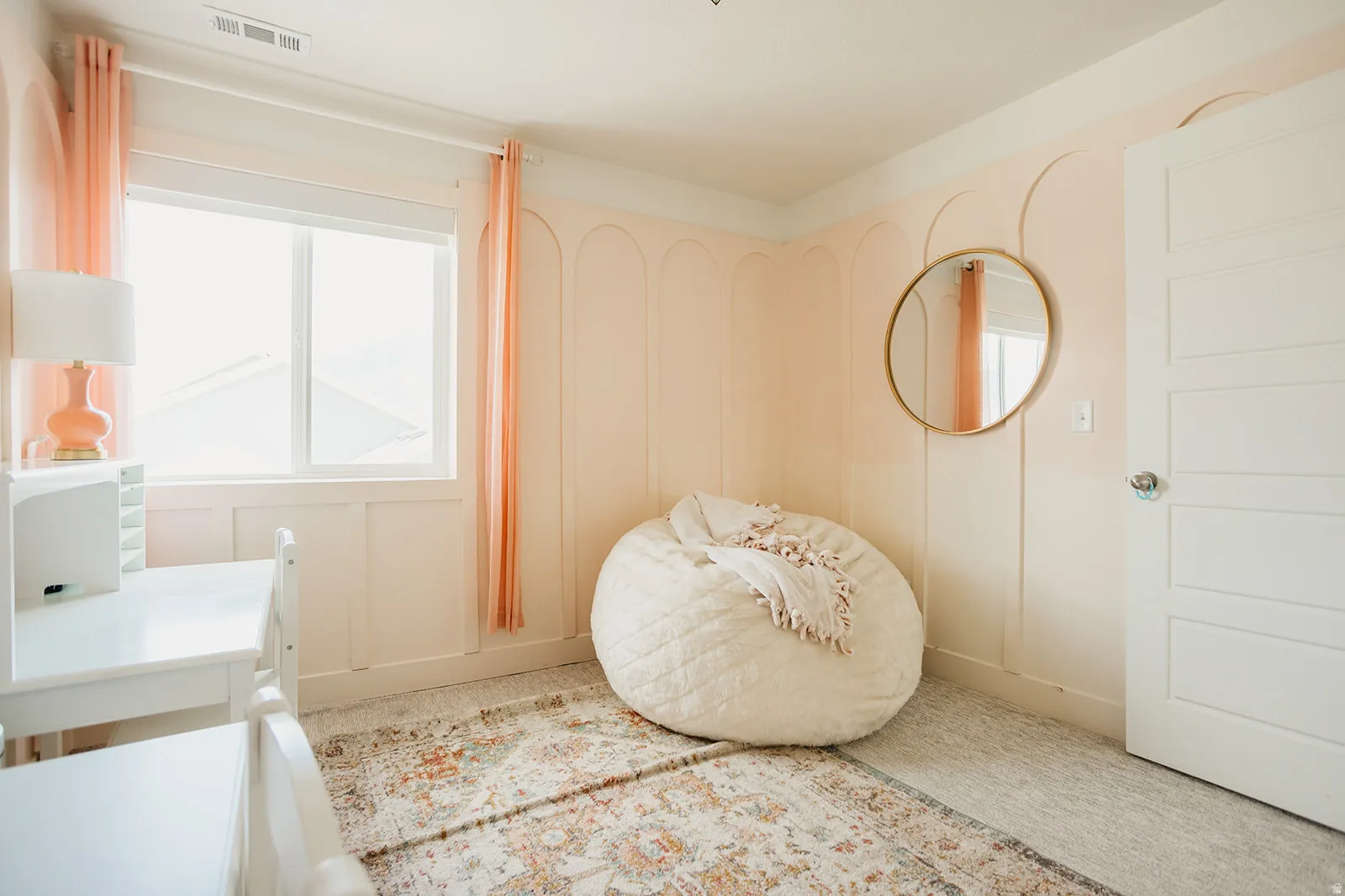 Window with white trim, light-colored walls with decorative paneling, light-colored flooring, and a white interior door