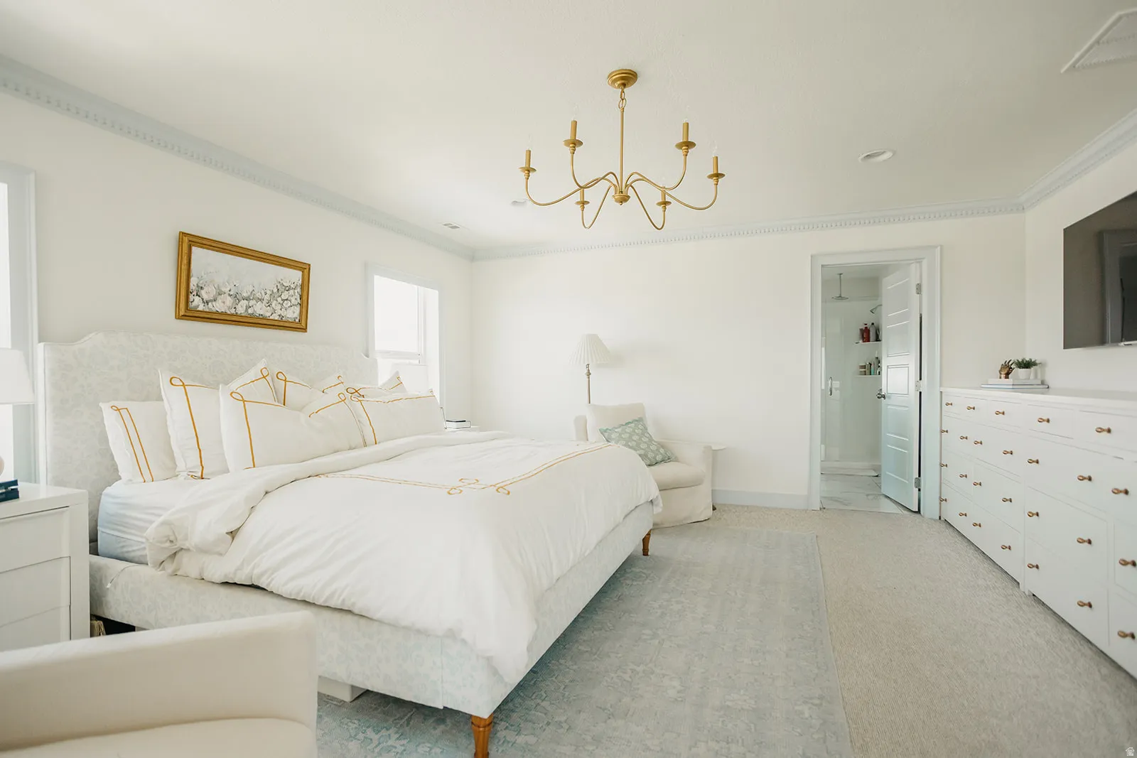 Recessed lighting and a gold-tone chandelier illuminate this room with crown molding