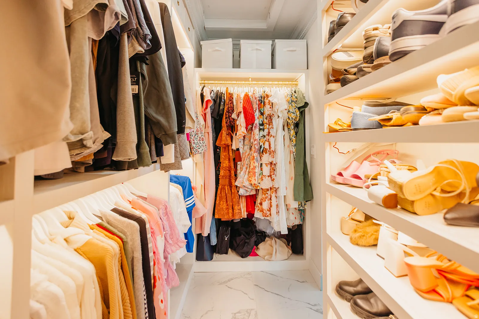 Walk-in closet featuring custom shelving, built-in hanging rods, integrated lighting, and marble-look flooring
