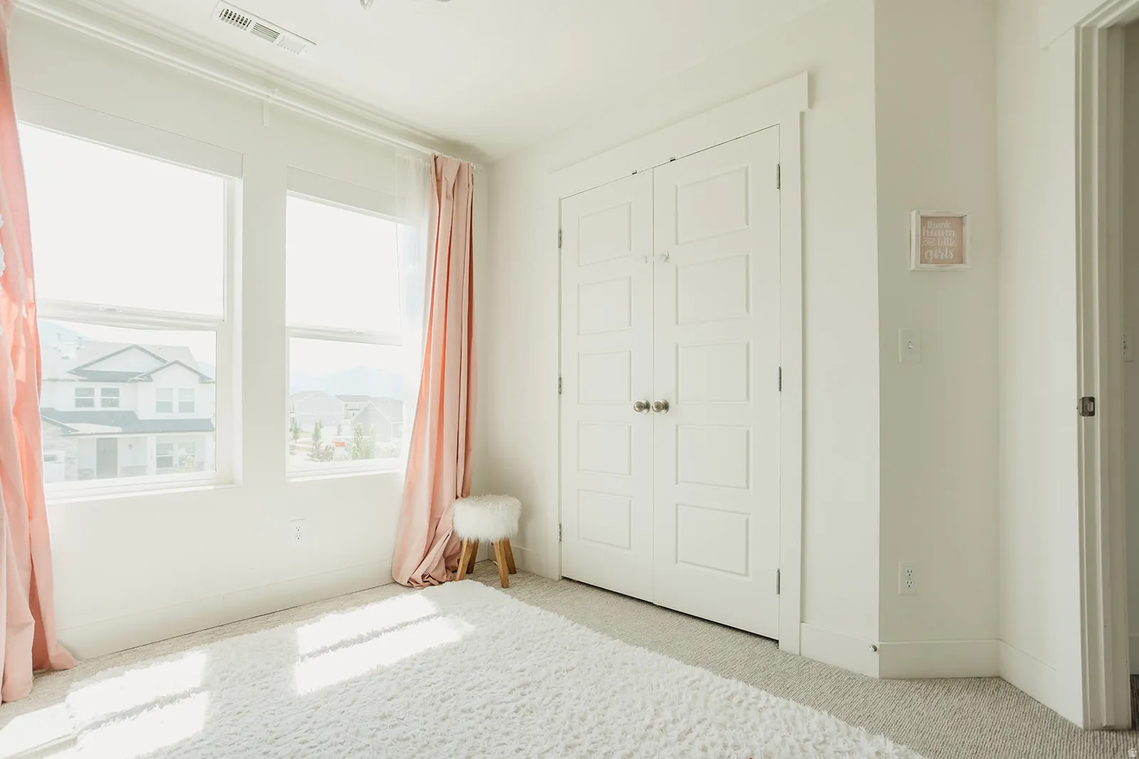 Bright interior space featuring dual windows, white trim work, and a closet with bifold doors