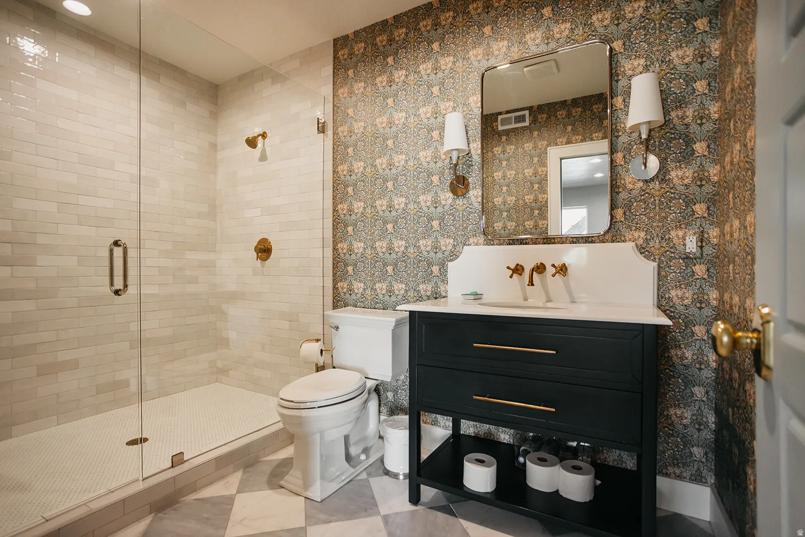 Glass-enclosed shower with subway tile surround, hexagonal tile shower floor, and brass fixtures