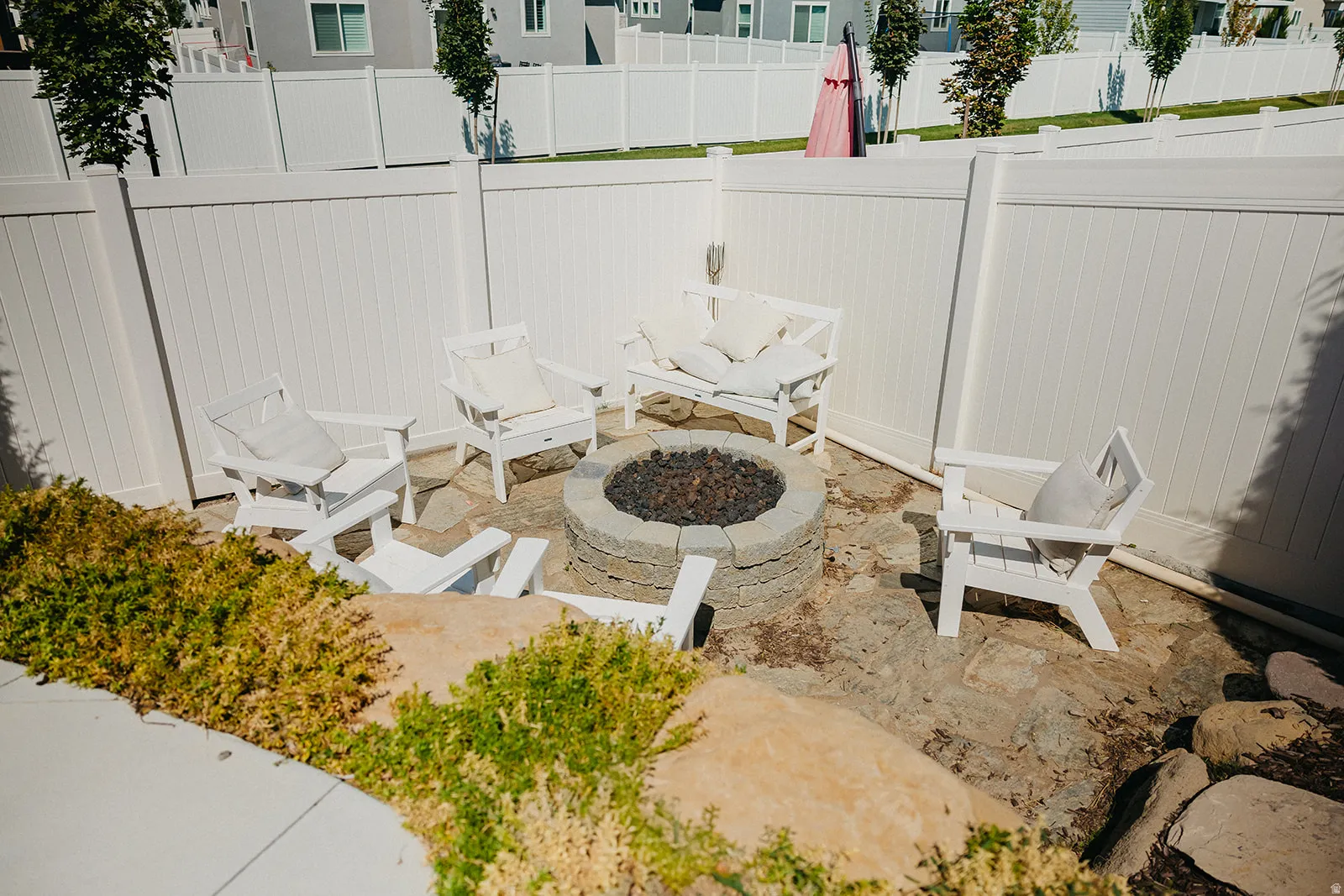 Stone fire pit area with flagstone paving and surrounding low-maintenance landscaping