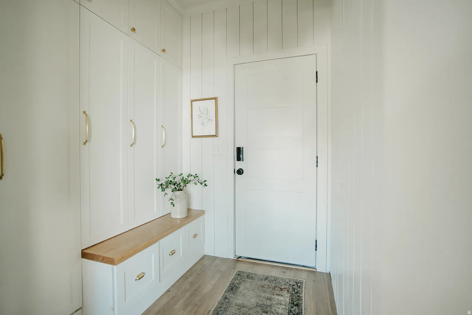 Built-in storage solutions with gold-finish hardware, wood-finish flooring, and white paneled walls