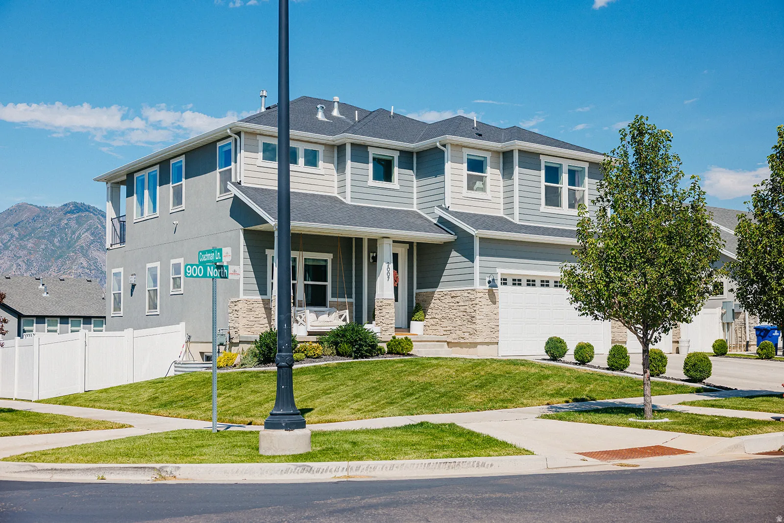 Contemporary exterior with light gray siding, stone accents, two-car garage, manicured lawn, and paved walkways