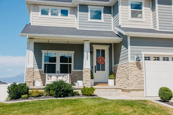 Welcoming front elevation featuring a two-story contemporary design with horizontal siding, stone veneer accents, and a covered entry portico