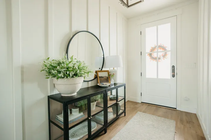 Vertical shiplap wall paneling, wood-finish flooring, white paneled door with glass inserts, and a contemporary ceiling-mounted light fixture