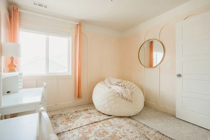 Window with white trim, light-colored walls with decorative paneling, light-colored flooring, and a white interior door