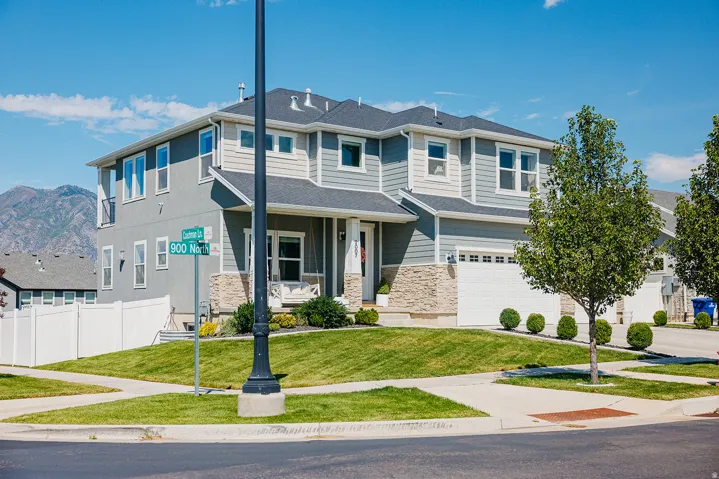 Contemporary exterior with light gray siding, stone accents, two-car garage, manicured lawn, and paved walkways