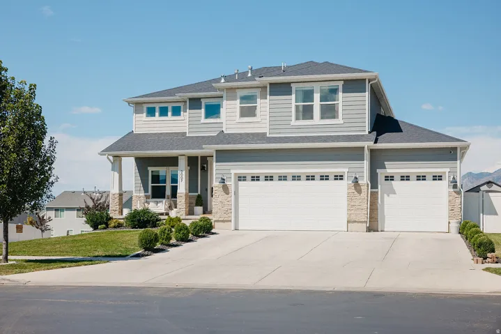 Two-story exterior with light gray siding and stone accents, covered entry, and two attached garages