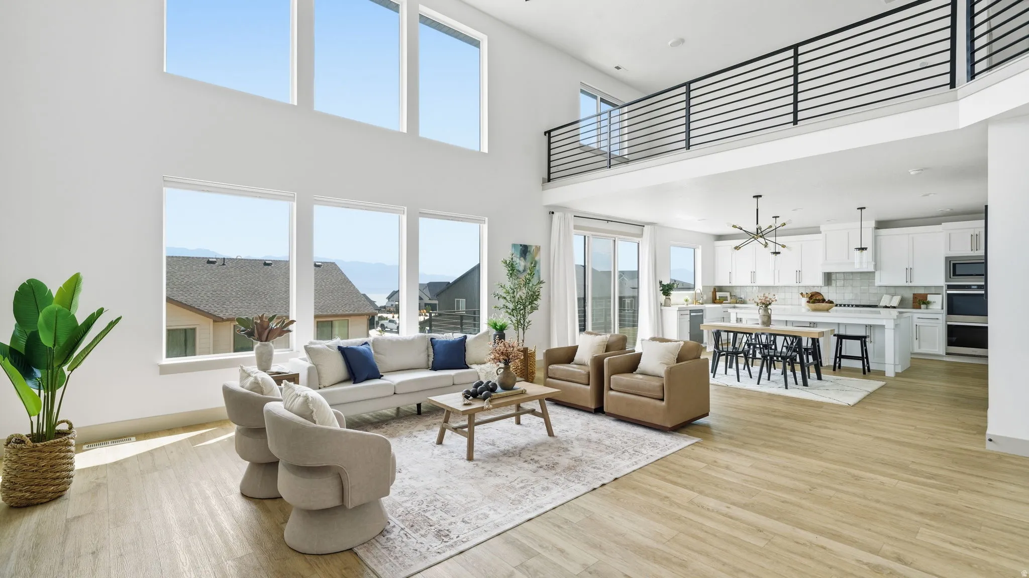Two-story living area with high ceilings, wood-finish flooring, a contemporary kitchen, and an open-concept design