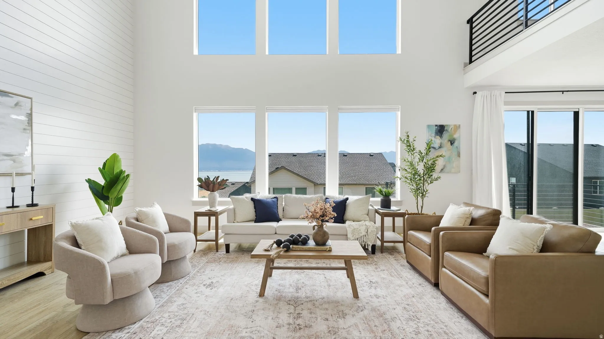 Vaulted ceilings with large windows, shiplap accent wall, and a multi-pane sliding glass door