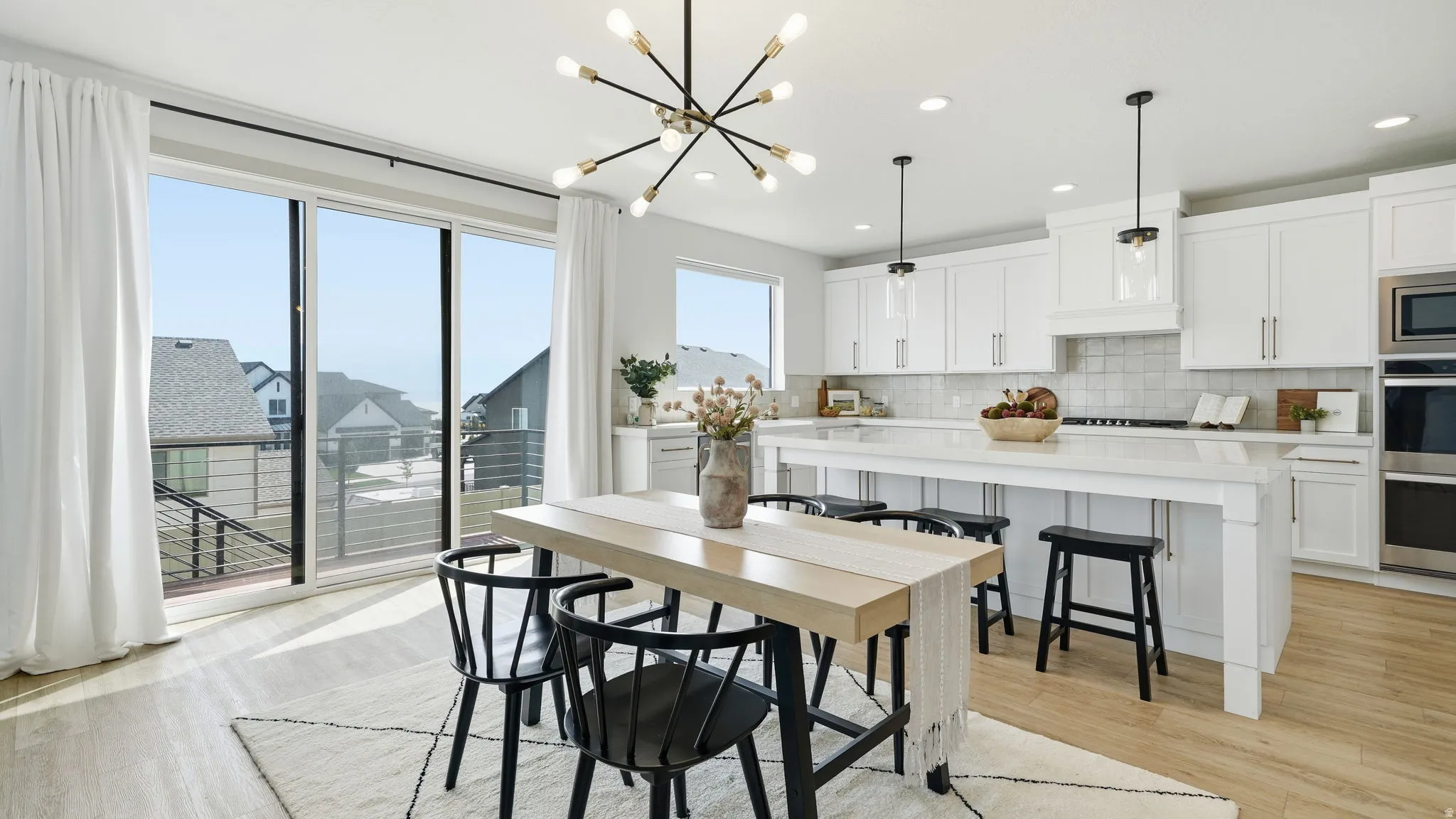 Spacious kitchen featuring white cabinetry, a large center island, stainless steel built-in appliances, and light wood-finish flooring