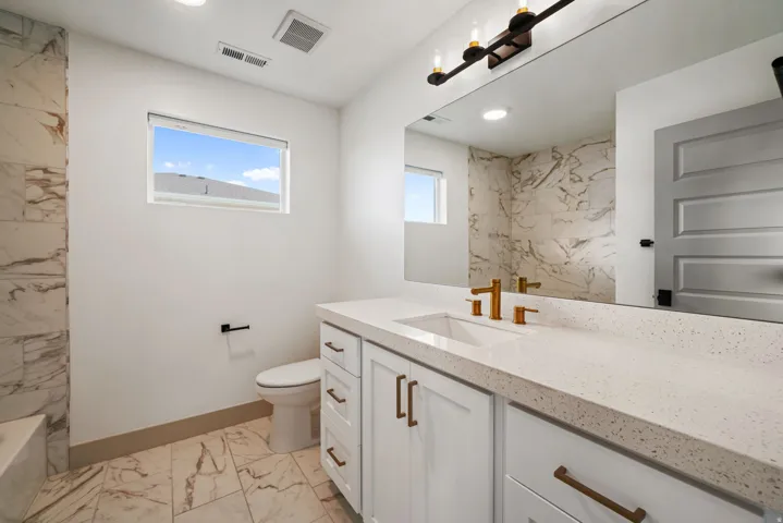 Vanity with an integrated sink, polished gold-finish fixtures, and a speckled countertop