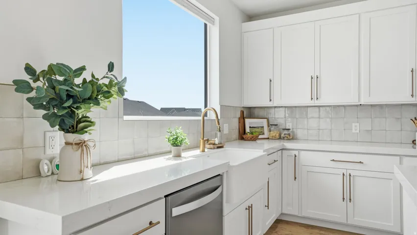White cabinetry with bronze hardware, white farmhouse sink, white countertops, square tile backsplash, and stainless steel dishwasher