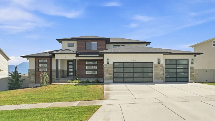Modern facade featuring wood-finish siding, stone accents, and light-toned stucco