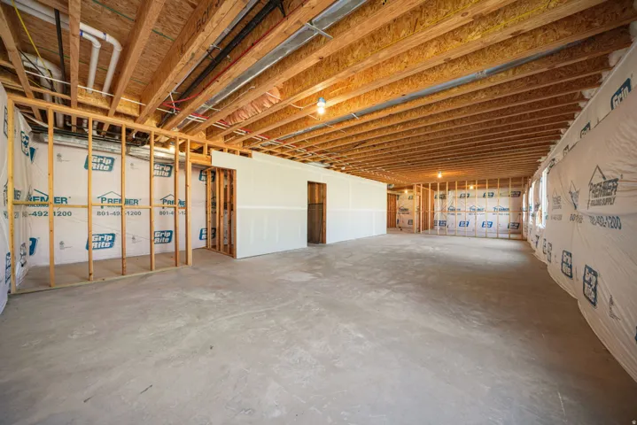 Unfinished basement with concrete flooring, exposed wood joists, and framed interior walls