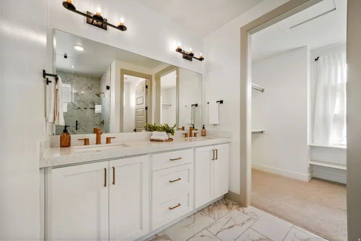 Dual vanity with white cabinetry, quartz-style countertop, and bronze-finish faucets