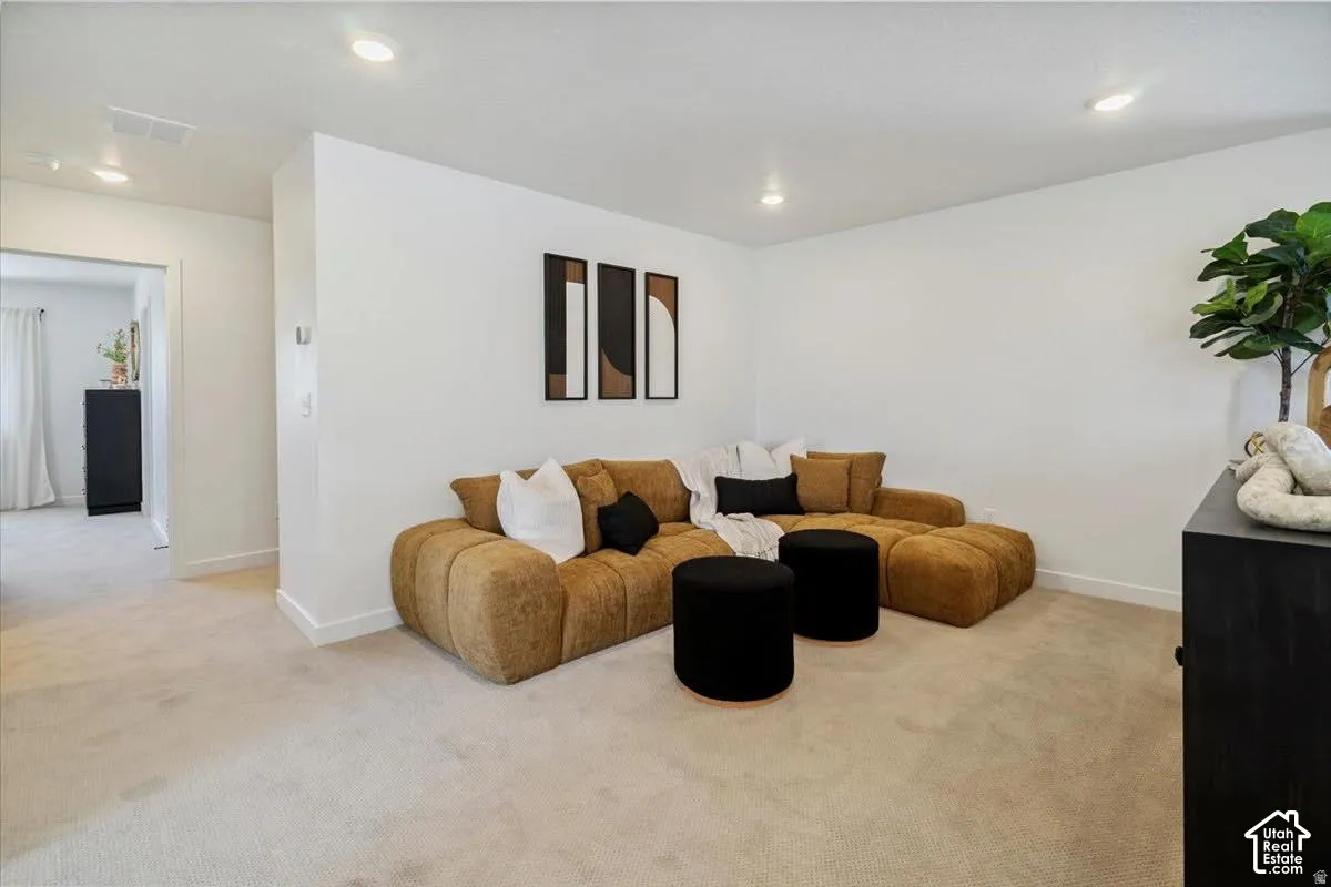 Recessed lighting illuminates a carpeted room with a wide doorway